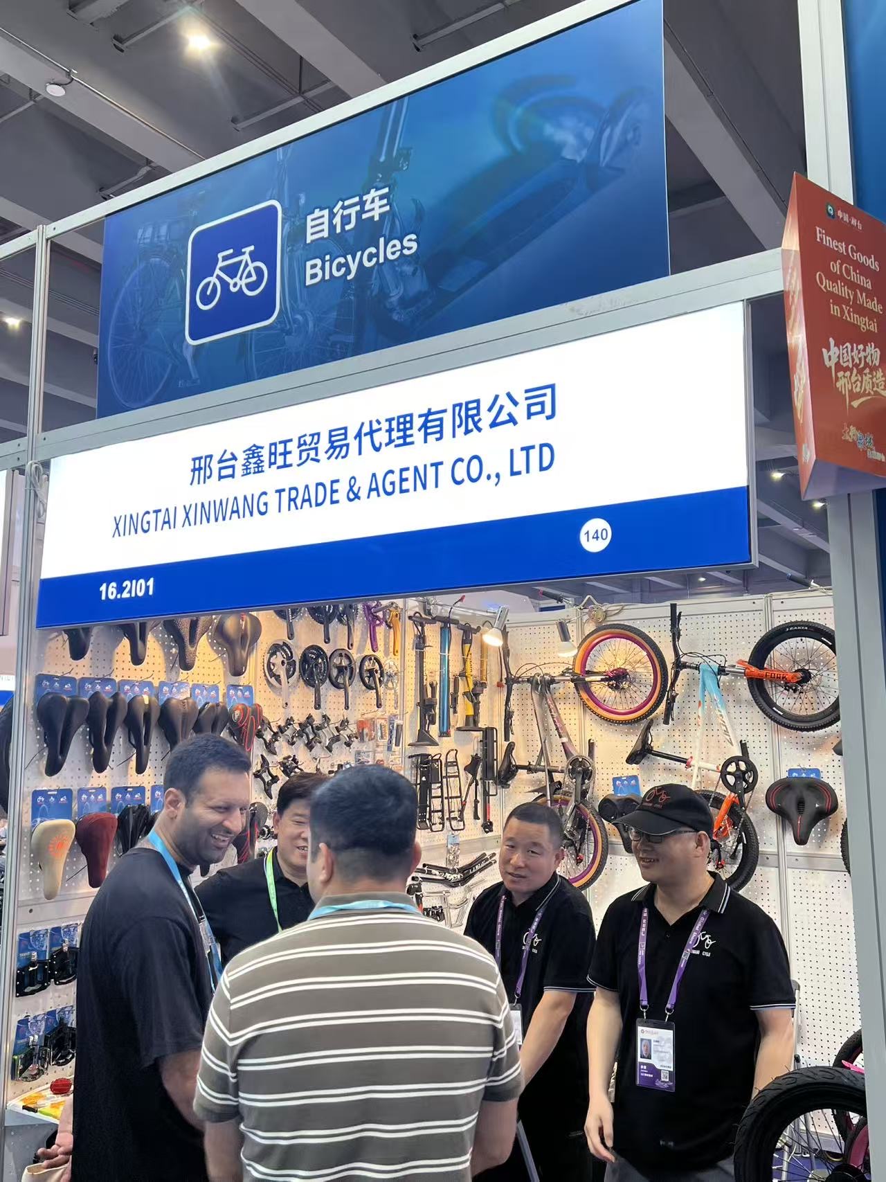 XINWANG CYCLE team speaking with visitors below the 140th Canton Fair sign at Booth 16.2I01